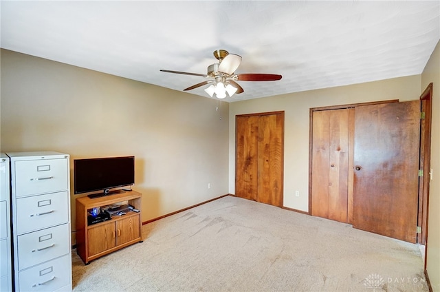 unfurnished bedroom featuring light carpet, two closets, and ceiling fan