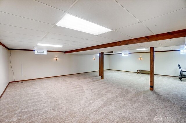 basement featuring a paneled ceiling, carpet, and a healthy amount of sunlight