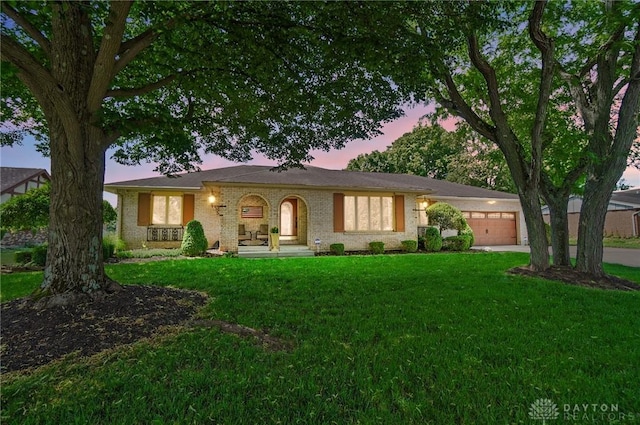 ranch-style house with a garage and a lawn