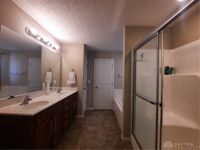 bathroom featuring a textured ceiling, shower with separate bathtub, and vanity