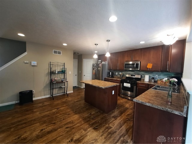 kitchen with hanging light fixtures, sink, appliances with stainless steel finishes, a center island, and dark hardwood / wood-style flooring