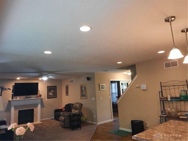 living room featuring dark wood-type flooring, ceiling fan, a fireplace, and a textured ceiling