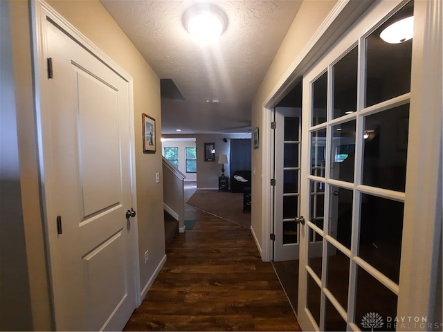 corridor featuring a textured ceiling and dark wood-type flooring