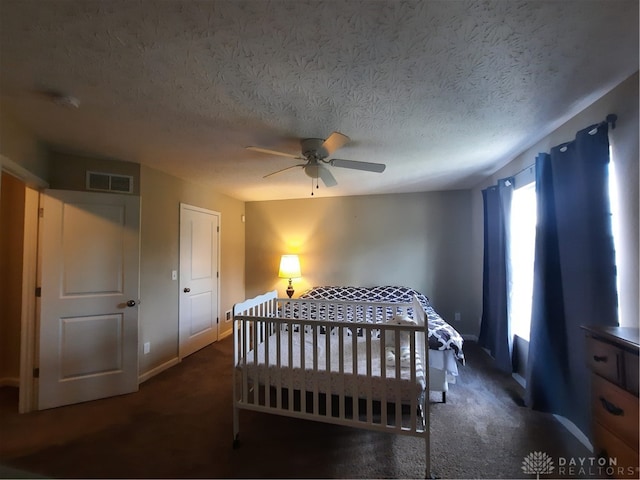 bedroom with dark carpet, ceiling fan, and a textured ceiling