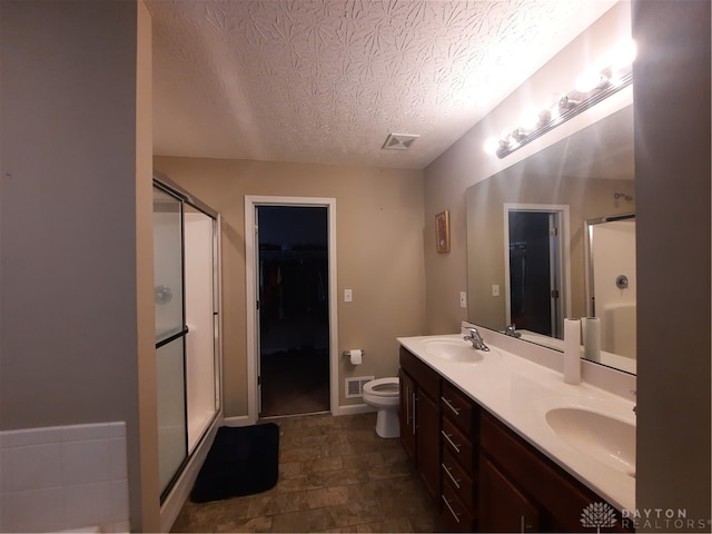 bathroom with a textured ceiling, a shower with door, toilet, and vanity