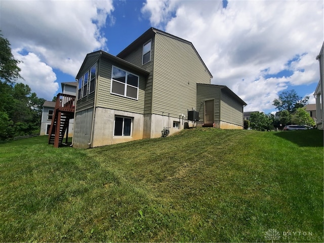 rear view of house with a deck, a yard, and central AC