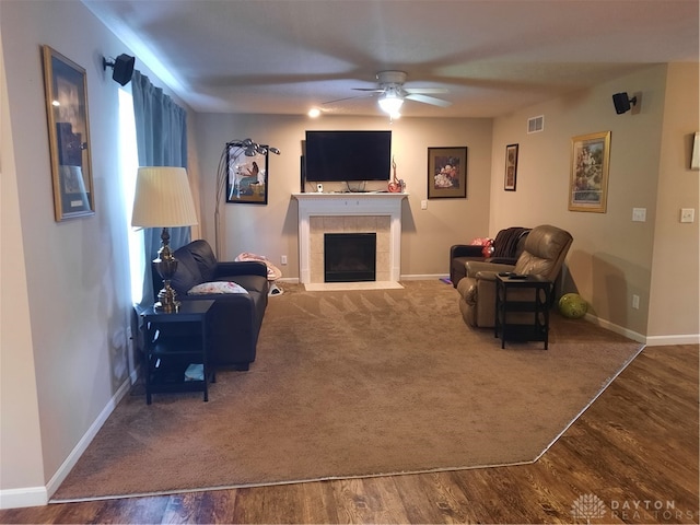 living room featuring ceiling fan, hardwood / wood-style flooring, and a tiled fireplace