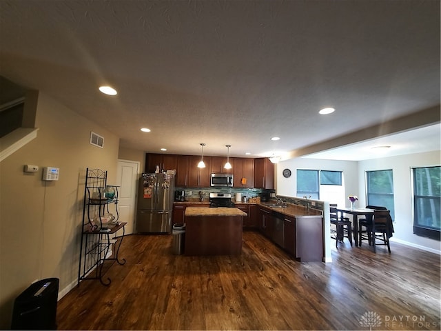 kitchen with hanging light fixtures, sink, dark wood-type flooring, stainless steel appliances, and a center island