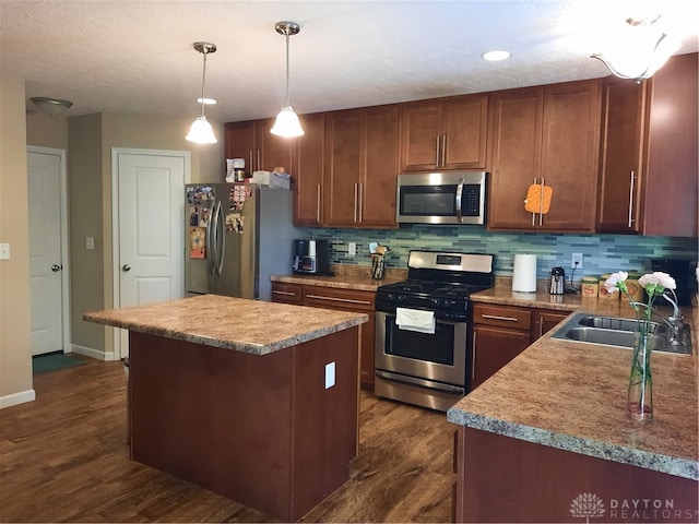 kitchen with sink, decorative light fixtures, dark wood-type flooring, appliances with stainless steel finishes, and decorative backsplash