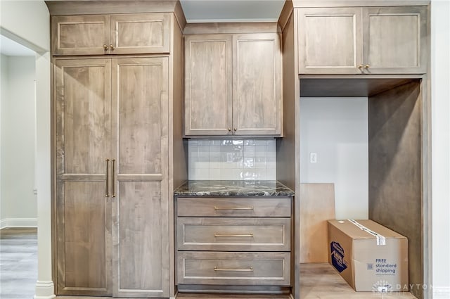 kitchen featuring light hardwood / wood-style floors, tasteful backsplash, and dark stone counters