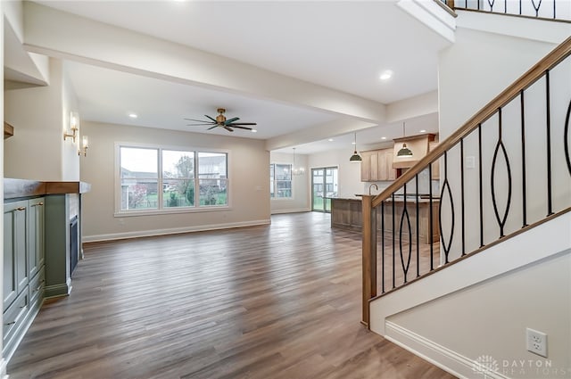 living room featuring ceiling fan with notable chandelier and dark hardwood / wood-style floors