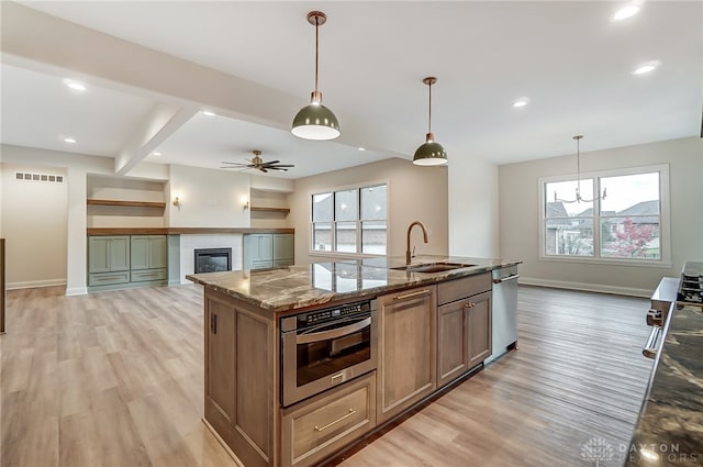 kitchen with a healthy amount of sunlight, light stone counters, a center island with sink, and stainless steel appliances