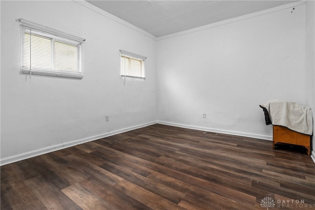 spare room with plenty of natural light, crown molding, and dark wood-type flooring