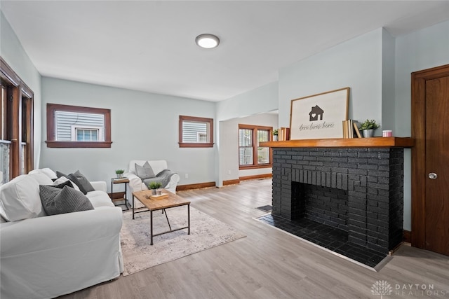 living room with light hardwood / wood-style flooring and a brick fireplace