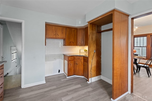 kitchen featuring light stone countertops, light wood-type flooring, and decorative backsplash