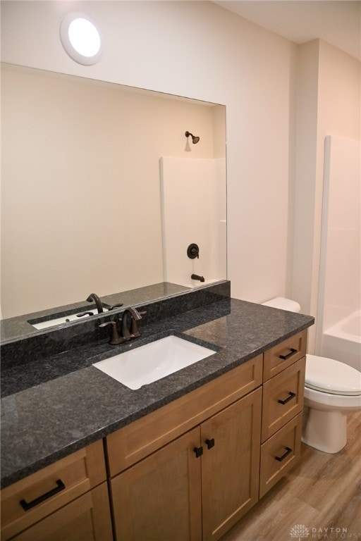 full bathroom with vanity, toilet, wood-type flooring, and washtub / shower combination