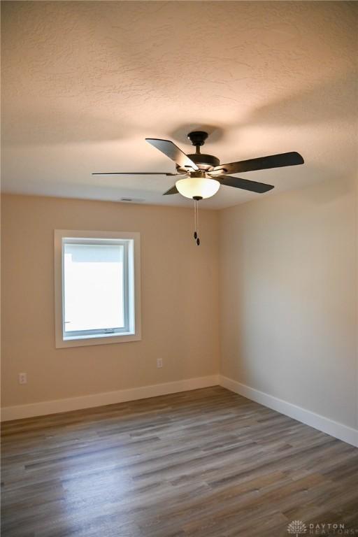spare room featuring a ceiling fan, baseboards, and wood finished floors