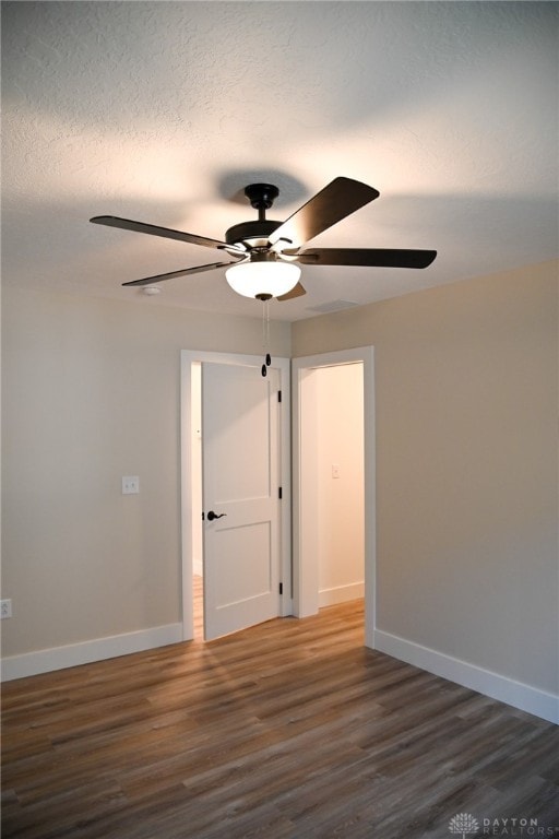 empty room with dark wood-type flooring, a textured ceiling, and ceiling fan