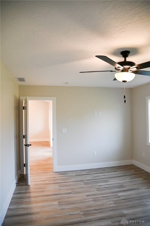 unfurnished room featuring ceiling fan, hardwood / wood-style flooring, and a textured ceiling