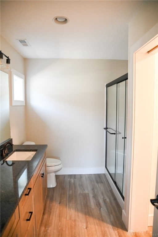 bathroom featuring vanity, a shower with shower door, wood-type flooring, and toilet