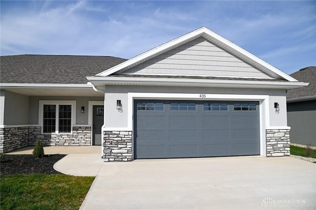 craftsman inspired home with roof with shingles, an attached garage, stone siding, stucco siding, and driveway