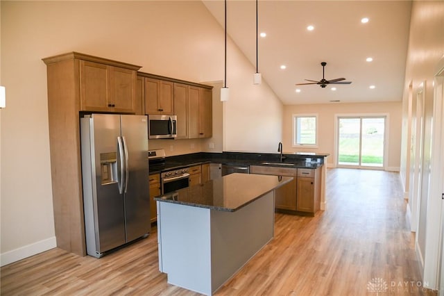 kitchen featuring ceiling fan, appliances with stainless steel finishes, a sink, high vaulted ceiling, and a peninsula