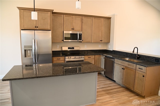 kitchen with sink, hanging light fixtures, light hardwood / wood-style floors, stainless steel appliances, and dark stone counters