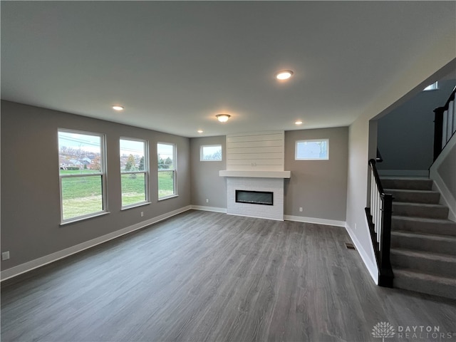 unfurnished living room with a large fireplace and dark hardwood / wood-style floors