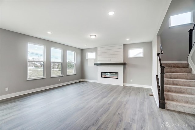 unfurnished living room featuring a fireplace, a wealth of natural light, and light wood-type flooring