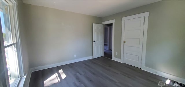 unfurnished bedroom featuring multiple windows and dark wood-type flooring