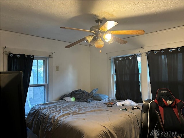 bedroom with ceiling fan and a textured ceiling