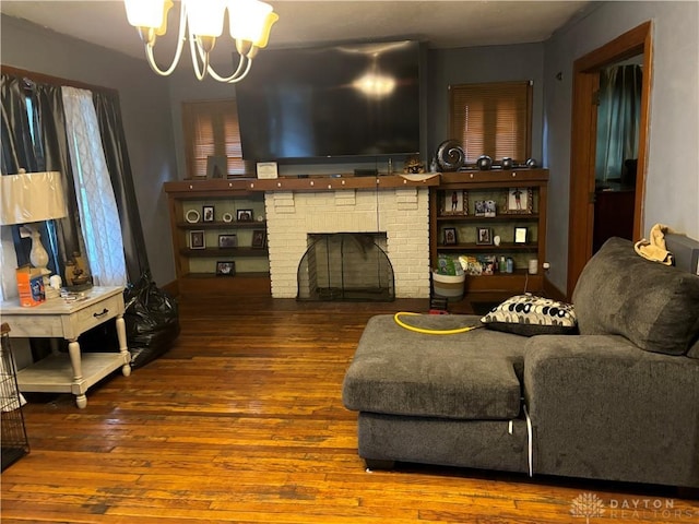 living room featuring a brick fireplace, an inviting chandelier, and wood finished floors