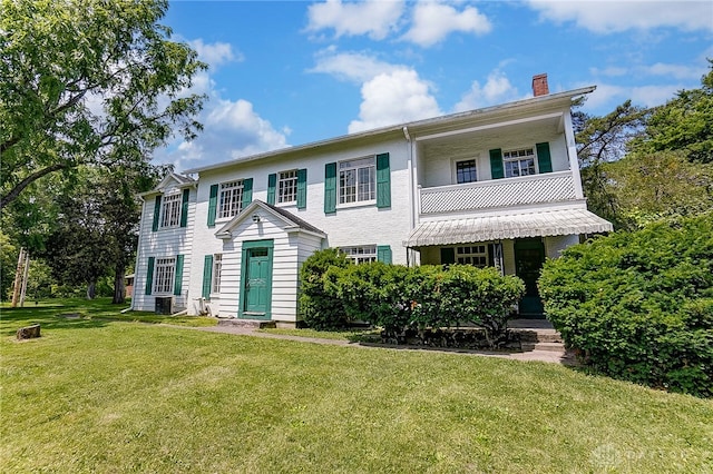 colonial home with a balcony and a front yard