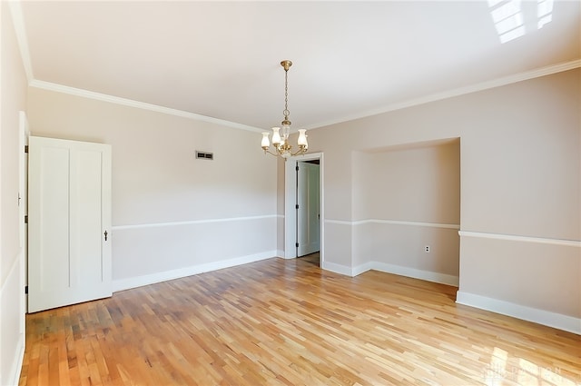 spare room featuring crown molding, light hardwood / wood-style flooring, and an inviting chandelier