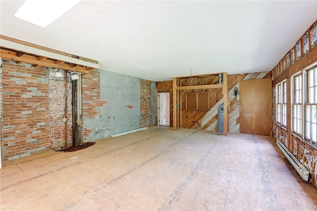 unfurnished living room featuring brick wall and a baseboard heating unit