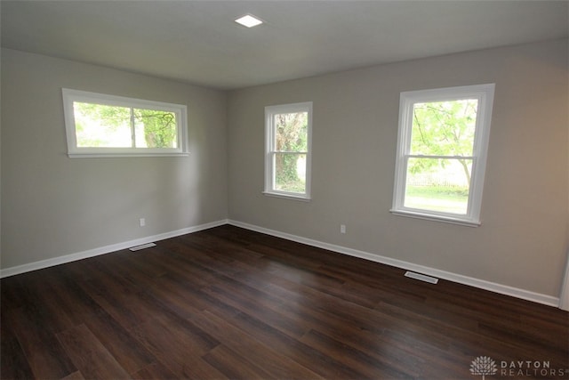 empty room with a healthy amount of sunlight and dark hardwood / wood-style floors