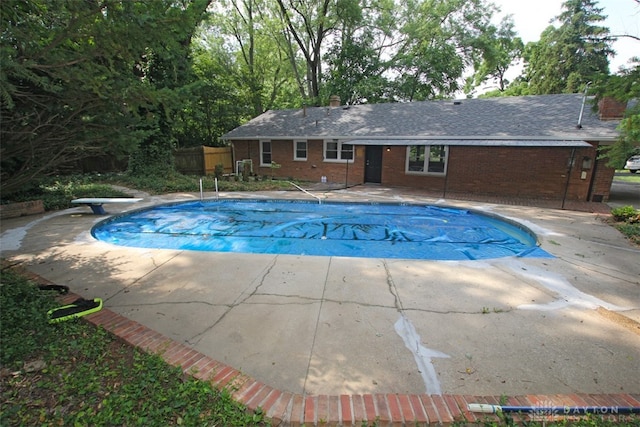 view of pool with a diving board and a patio