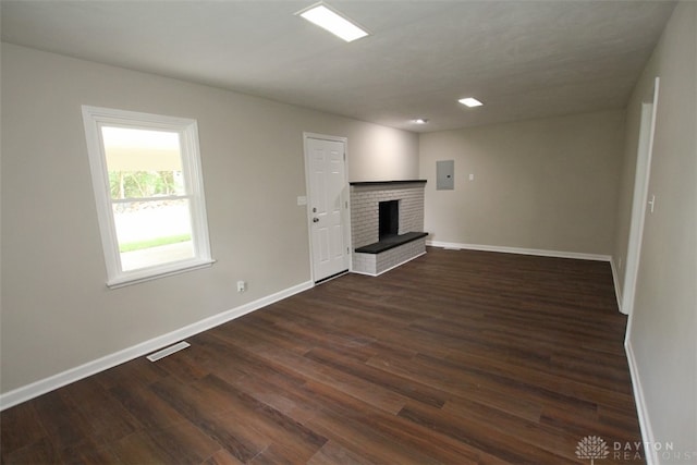 unfurnished living room featuring a fireplace, electric panel, and dark wood-type flooring