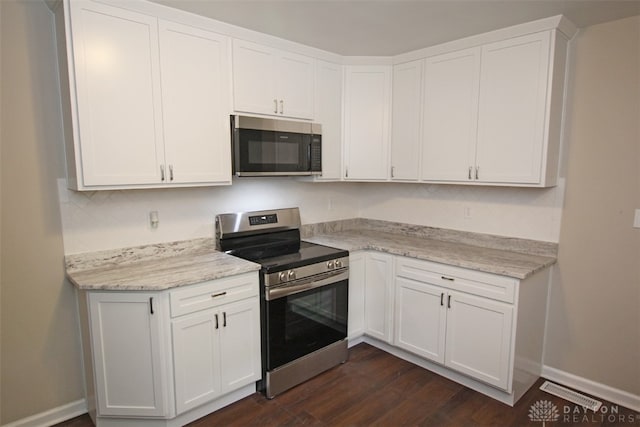 kitchen featuring white cabinets, light stone countertops, stainless steel appliances, and dark wood-type flooring