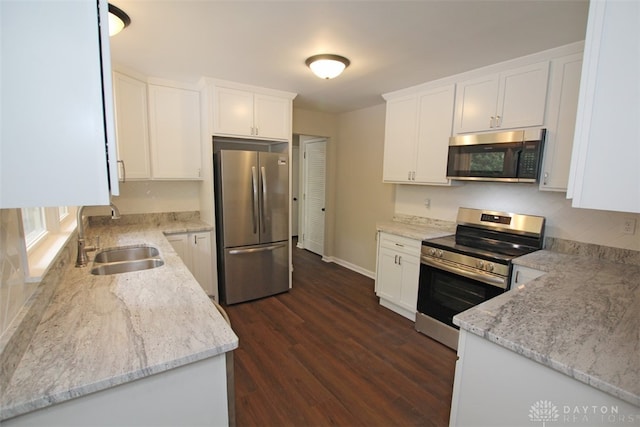 kitchen with light stone countertops, stainless steel appliances, dark wood-type flooring, sink, and white cabinetry