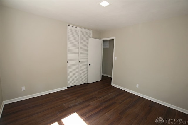 unfurnished bedroom featuring a closet and dark hardwood / wood-style floors