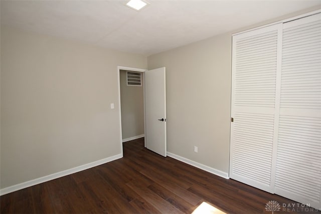 unfurnished bedroom featuring a closet and dark wood-type flooring