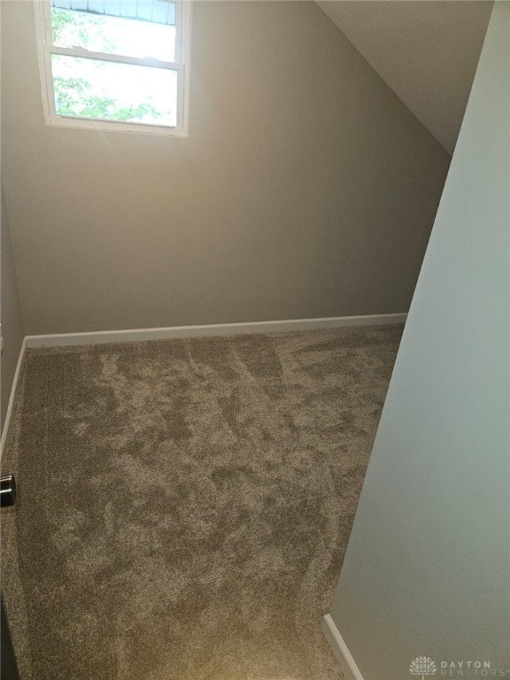 unfurnished room featuring carpet flooring and vaulted ceiling