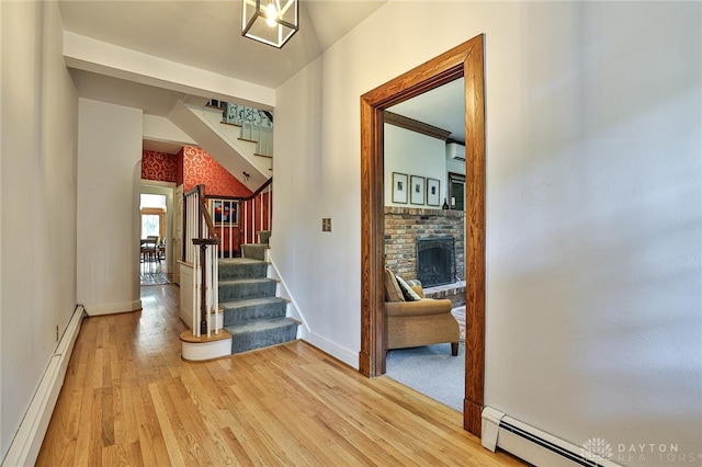 corridor featuring wood-type flooring and a baseboard heating unit