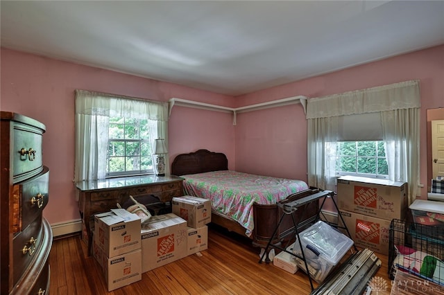 bedroom with hardwood / wood-style flooring and a baseboard heating unit