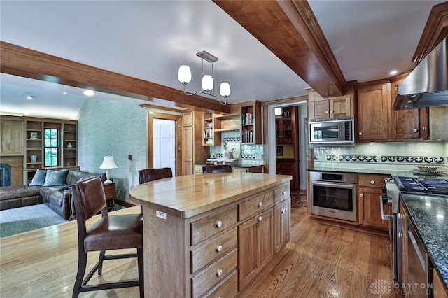 kitchen featuring decorative backsplash, stainless steel appliances, decorative light fixtures, light hardwood / wood-style flooring, and a kitchen island