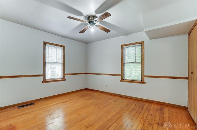 unfurnished room with ceiling fan, light wood-style flooring, visible vents, and baseboards