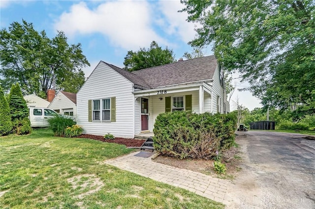 view of front of house with a shingled roof and a front yard