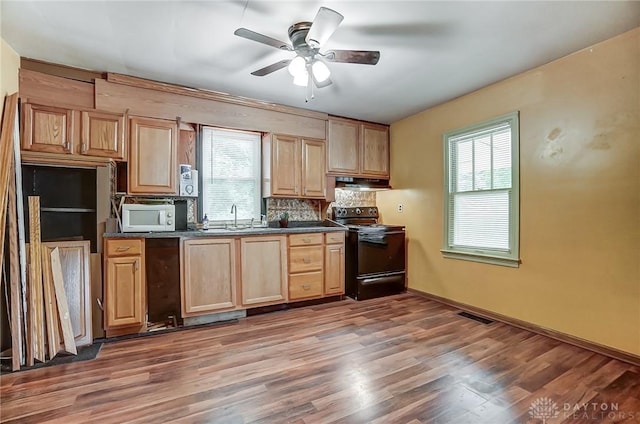 kitchen featuring visible vents, dark countertops, black electric range, under cabinet range hood, and a sink