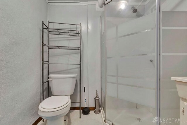 bathroom with tile patterned flooring, toilet, and an enclosed shower